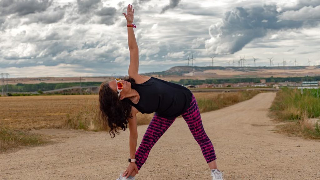 Outdoor fitness scene of a woman stretching on a dirt path in Soto de Cerrato amidst scenic landscapes.